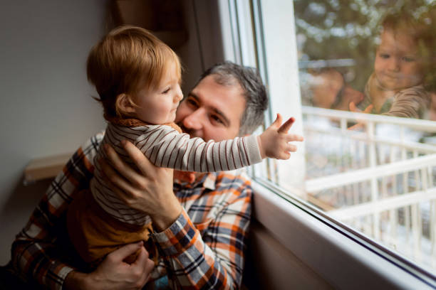 istock Baby boy pointing through the window while his father holds him 1313735365