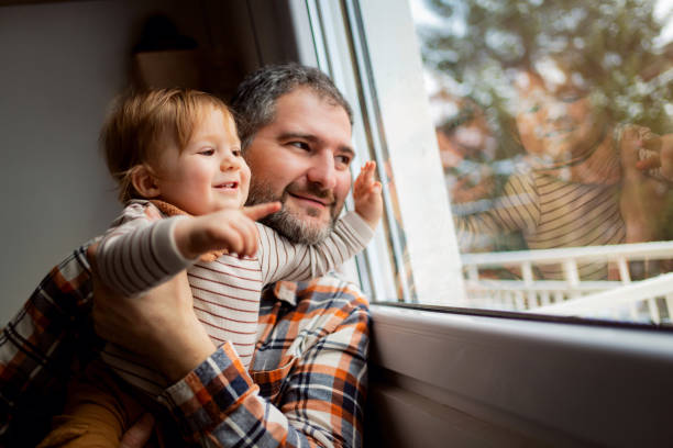 istock Smiling father and his baby son looking through the window 1313735379