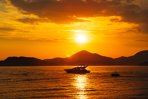 White motor yacht sails on the sea against the background of mountains at sunset. High quality photo
