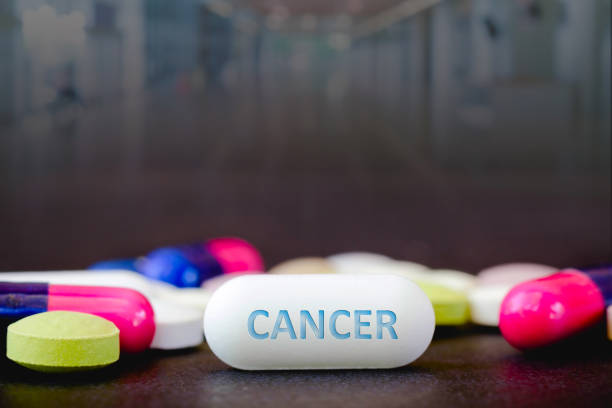 на этой фотоиллюстрация таблетки фармацевтических препаратов различных цветов. текст cancer в одной белой таблетке. концепция здравоохранен� - anti cancer стоковые фото и изображения
