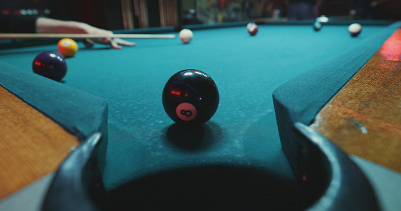 A setting of a pool game, focusing the black ball. It's close to the hole and hopefully will stay there until the very end.