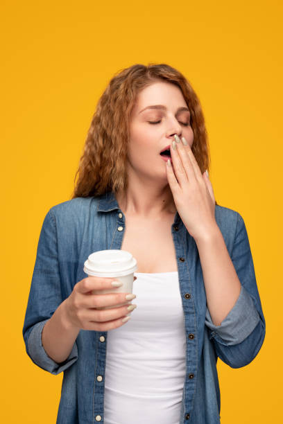 donna sbadigliante con caffè da asporto - yawning women drink coffee cup foto e immagini stock