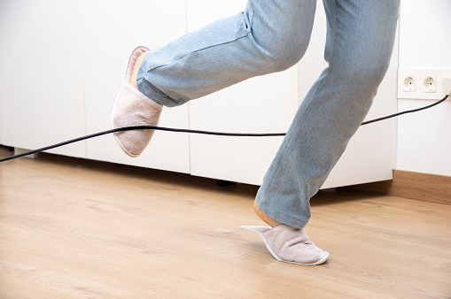 Close up of a woman legs stumbling with an electrical cord at home