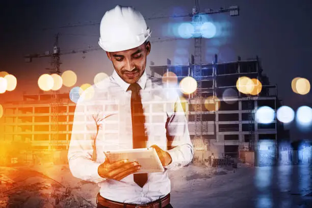 Photo of Shot of a building contractor using his tablet superimposed over a build site