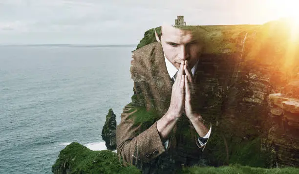 Photo of Shot of a focussed young businessman superimposed over a beautiful landscape