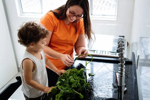 Mother and son washing vegetables in the kitchen