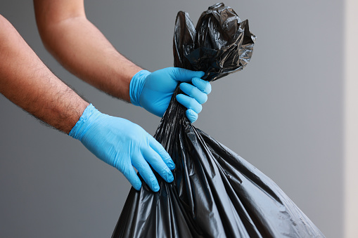 The young man separated the dangerous waste into a large black bag and put it in the trash. The correct sorting of waste Household waste
