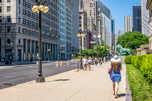 Chicago, IL / USA - June 6, 2020: A young, stylish woman enjoys walking along Michigan Avenue on a summer day, despite business closures and shelter in place orders across the city because of Covid-19
