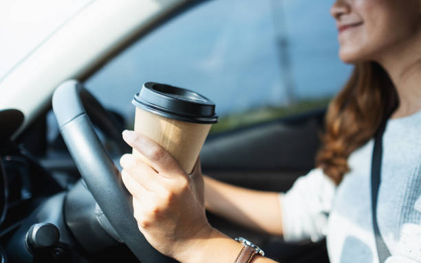 istock a woman holding and drinking coffee while driving a car 1313768443