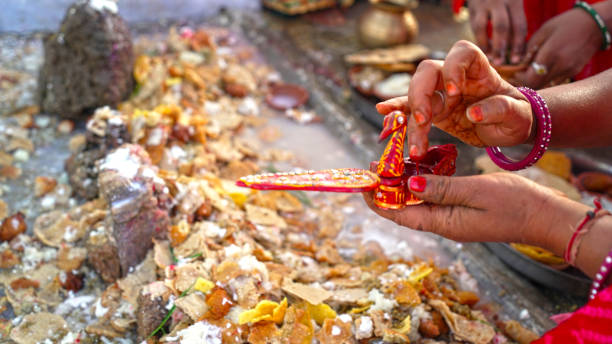 Woman hand offering religious prayer to God temple. Sacred food holding on ground near god statue. stock photo