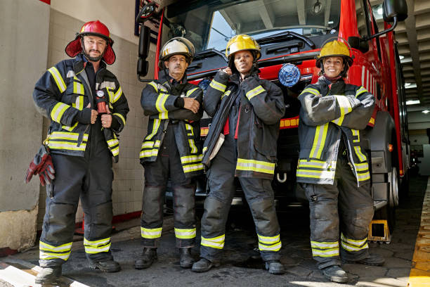 outdoor portrait of diverse firefighters at engine house - feuerwache stock-fotos und bilder