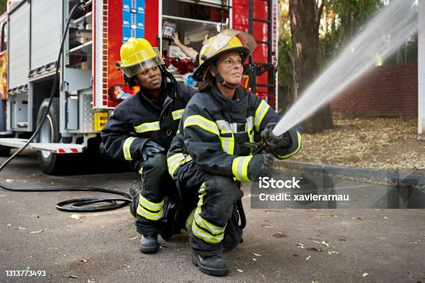 Mid Adult Female Hose Team Working At Emergency Site Stock Photo - Download Image Now