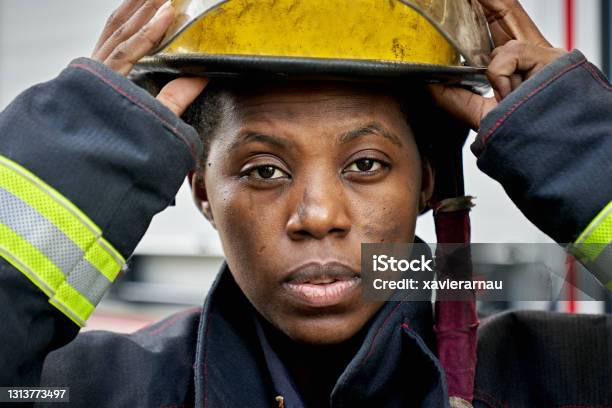 Portrait Of Black Female Firefighter Putting On Helmet Stock Photo - Download Image Now