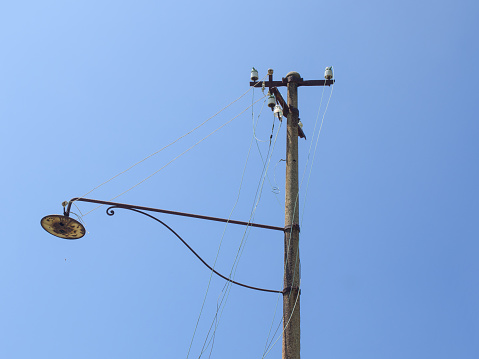 old abandoned street light, wit hbroken wires, blue sky in background