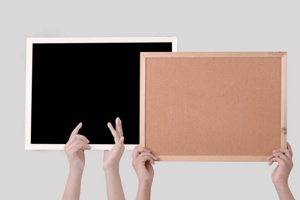 istock Human hand holding a brown cork board in a frame and blackboard 1313782322