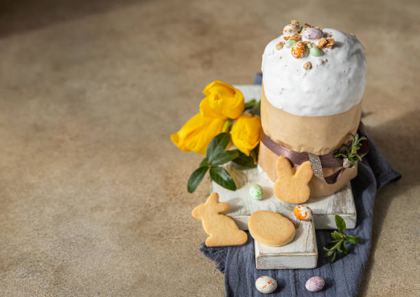 istock Easter composition with traditional Orthodox sweet bread. Kulich decorated with meringue icing, candy shaped eggs, easter cookies and tulip. 1313782795