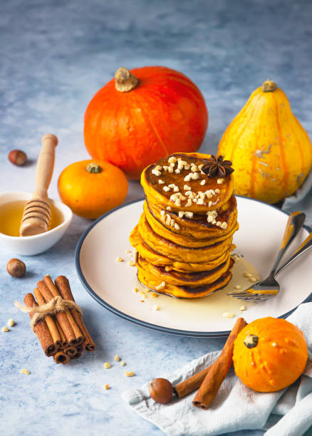 istock Stack of delicious pumpkin fluffy pancakes with maple syrup or honey and nuts. Healthy breakfast. Autumn food. Blue background. 1313783367