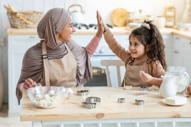 istock Arab Mom Giving High Five To Little Daughter While Baking In Kitchen 1313785687