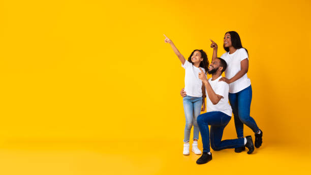 istock Smiling black family pointing aside at copy space at studio 1313785786