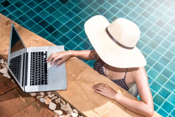 istock Beautiful smiling woman using laptop computer in swimming pool 1313785846