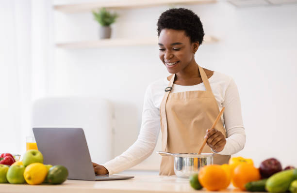 istock Black Woman Cooks Using Laptop Searching Recipes Online In Kitchen 1313787067