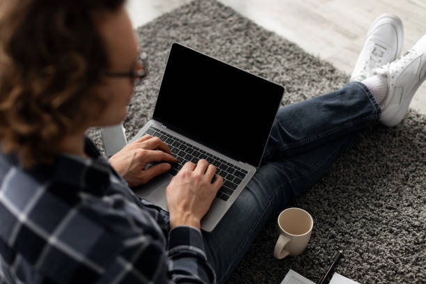 istock Back-View Of Guy Using Laptop With Blank Screen Sitting Indoor 1313787122