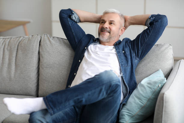 istock Happy bearded senior man relaxing on couch at home 1313787264