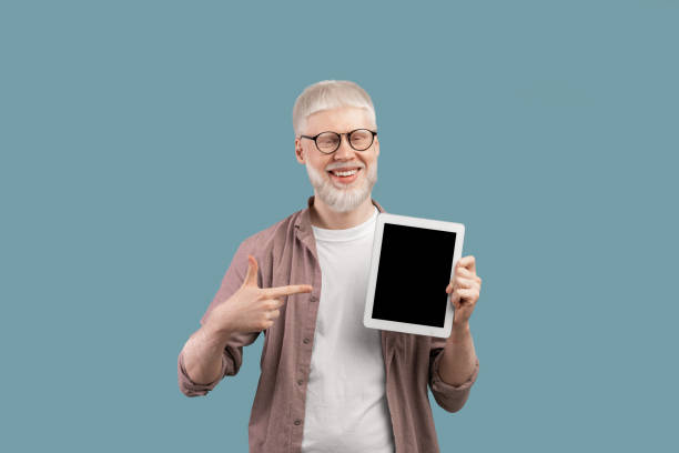 istock Happy albino man pointing at blank tablet screen with space for website or app design over turquoise background 1313787367