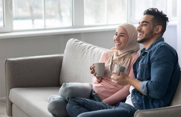 istock Joyful arab couple drinking coffee and looking at copy space 1313787461