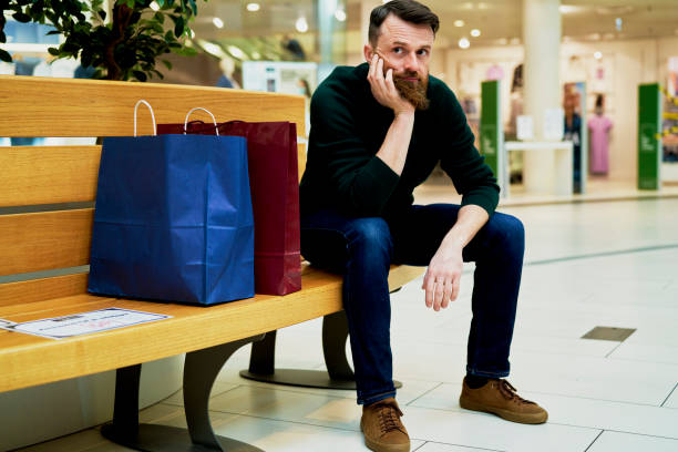 istock Bored man sitting on bench in shopping mall 1313787615