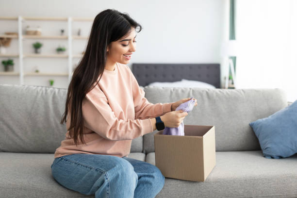 istock Smiling young lady unpacking parcel after online shopping 1313787896