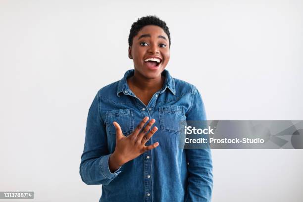 Portrait of casual young black woman laughing, white wall