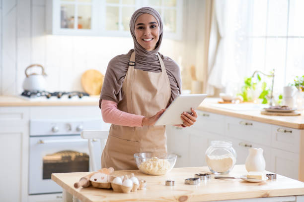 istock Young Islamic Lady In Hijab And Apron Using Digital Tablet In Kitchen 1313789285
