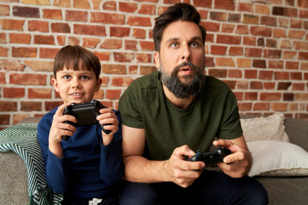 istock Focused father and son playing video game together 1313790473