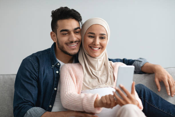 istock Happy expecting muslim couple taking selfie on smartphone while relaxing at home 1313790870