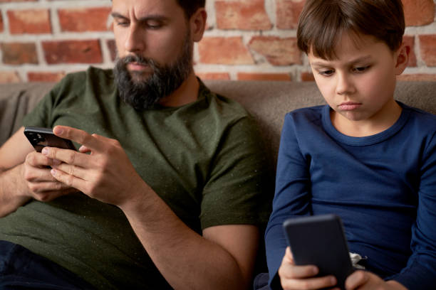 istock Close up of boredom father and son using mobile phone 1313791821