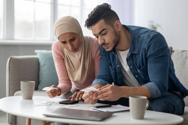 istock Confusded lady in hijab and her upset husband with bills 1313791943