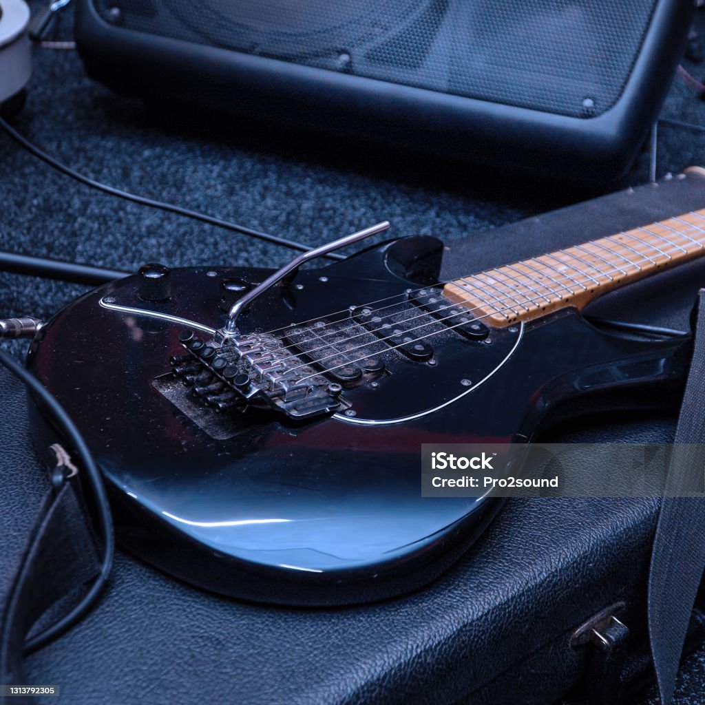 Black electric guitar with tremolo on a hard case Black electric guitar with tremolo on a hard case. Selective focus Guitar Stock Photo