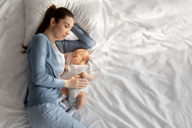 con acostarse con el bebé. joven durmiendo la siesta en la cama con su hijo recién nacido - imagenes de embarazadas bonitas fotografías e imágenes de stock