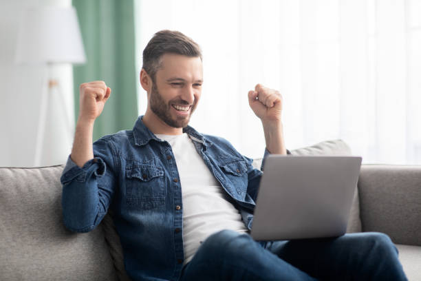istock Emotional bearded man celebrating success, using laptop 1313792408