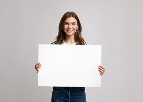 Sonriente millennial señora sosteniendo cartel en blanco con espacio de copia para la publicidad photo