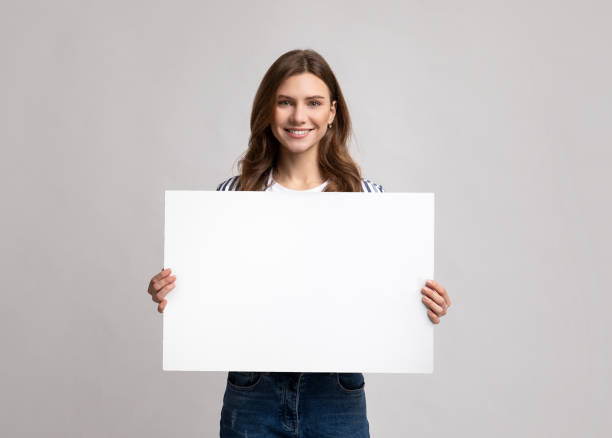 dame millénaire de sourire retenant le signe blanc avec l’espace de copie pour la publicité - pancarte de manifestation photos et images de collection