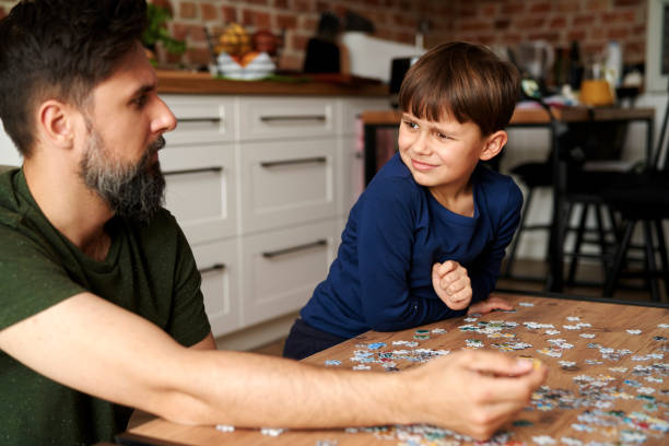 istock Father and son sitting and solving jigsaw puzzle 1313792982