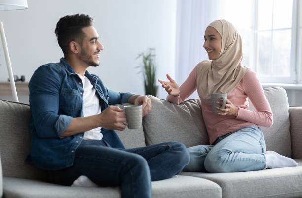 istock Young muslim couple drinking coffee and having conversation at home 1313793566
