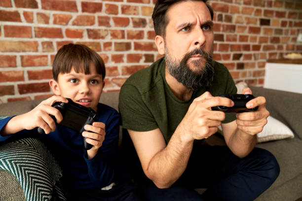 istock Focused father and son sitting and playing video game together 1313793725