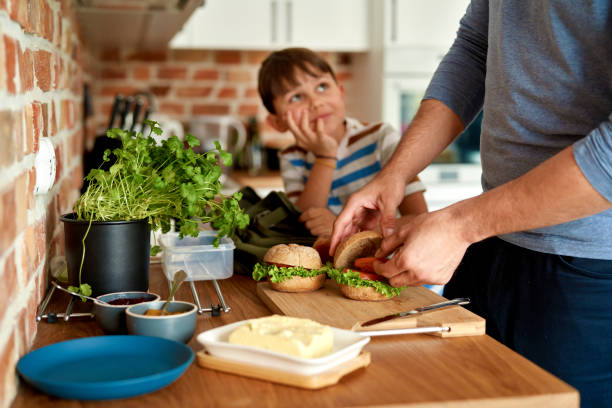 Close up of father making lunch for son in kitchen Close up of father making lunch for son in kitchen making a sandwich stock pictures, royalty-free photos & images