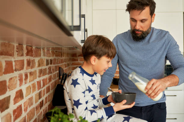istock Father pours milk into breakfast cereal for his son 1313794044