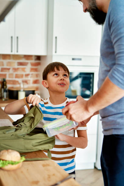 istock Father and son packing healthy food lunch boxes for school 1313794105