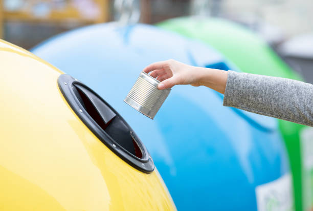 istock Garbage Sorting Concept. Female throwing metal can into yellow recycle bin outdoors 1313794375