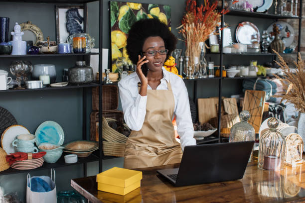 istock Afro saleswoman talking on mobile and typing on laptop 1313796680